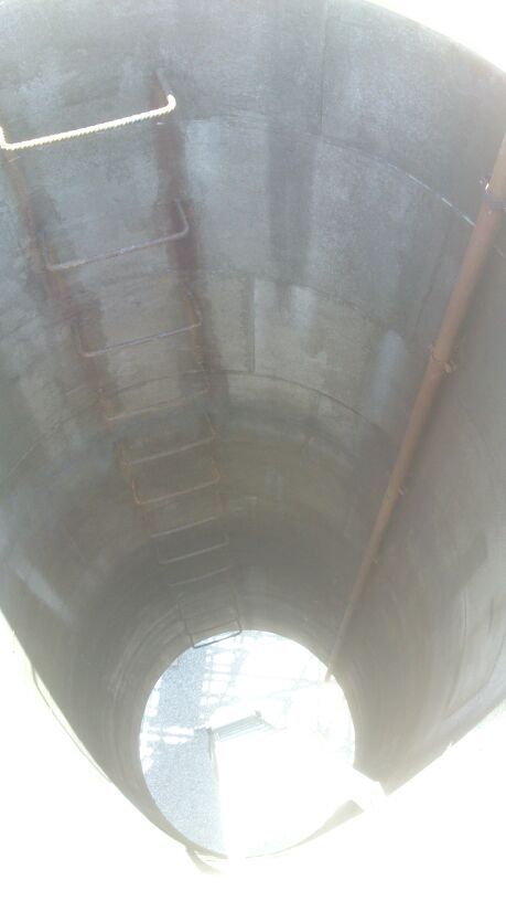 El interior de un gran barril negro con una escalera y un agujero en el medio.