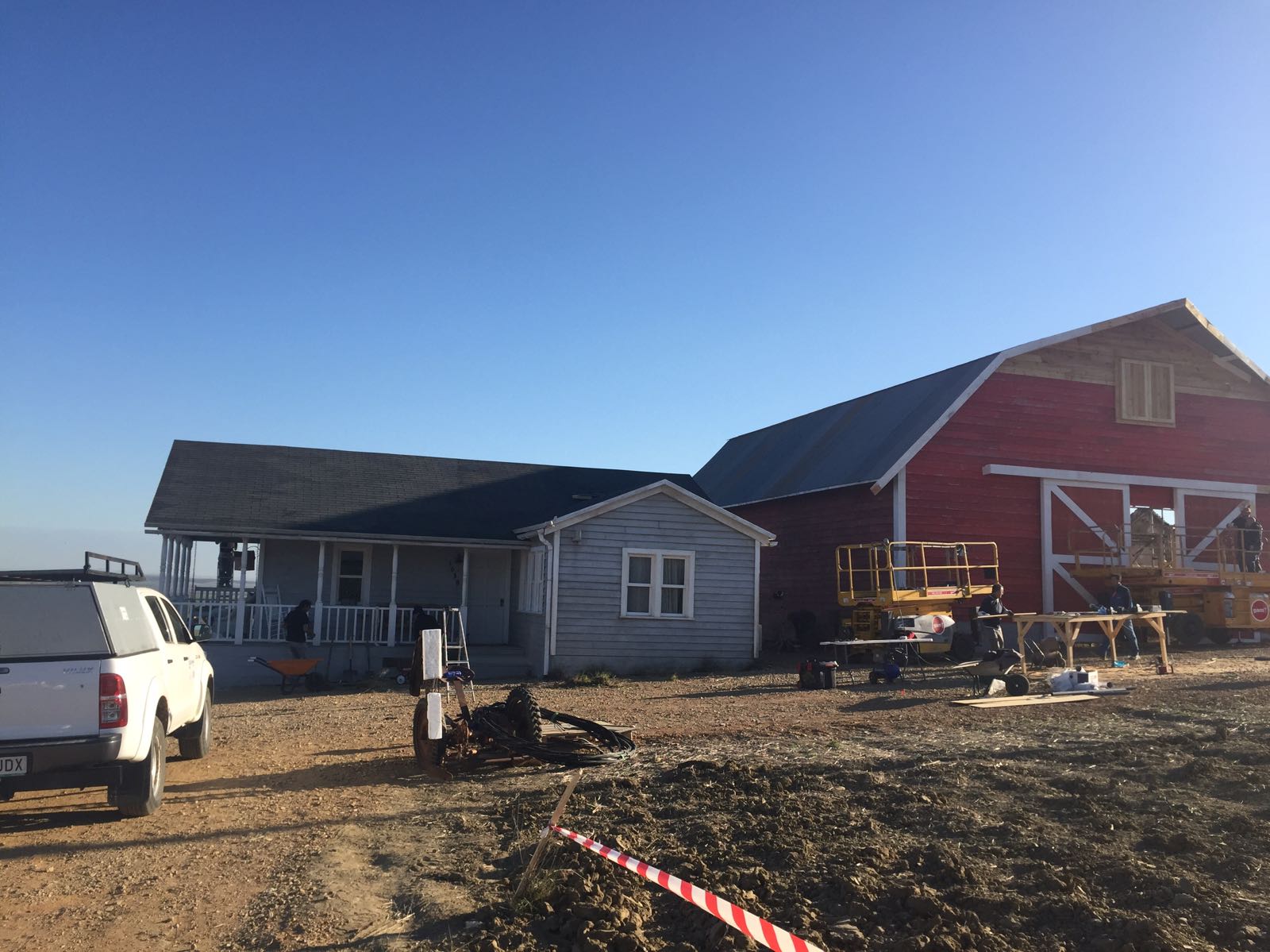 Un camión blanco está estacionado frente a una casa y un granero.