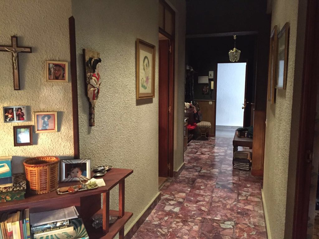 Un pasillo con cuadros en la pared y una cruz en la pared.