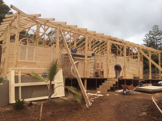 Se está construyendo una casa de madera con una carretilla delante de ella.