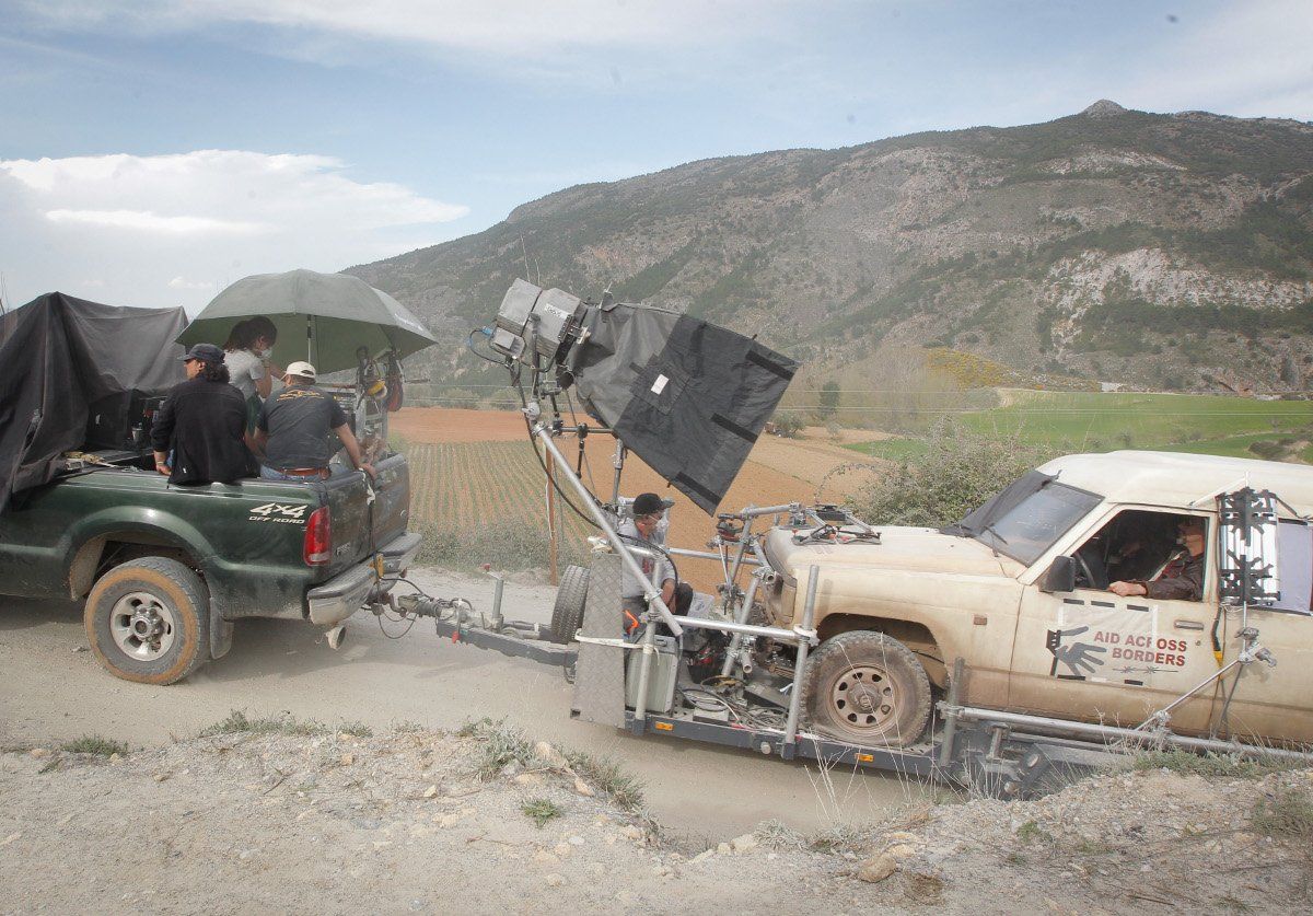 Un camión está siendo remolcado por otro camión en un camino de tierra.