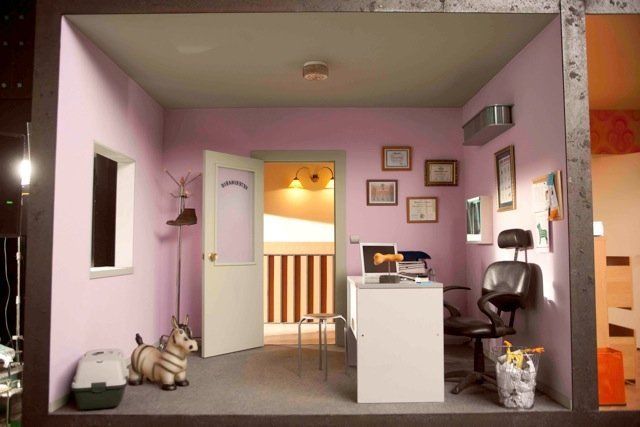 Una habitación con paredes rosas y un escritorio y una silla blancos.