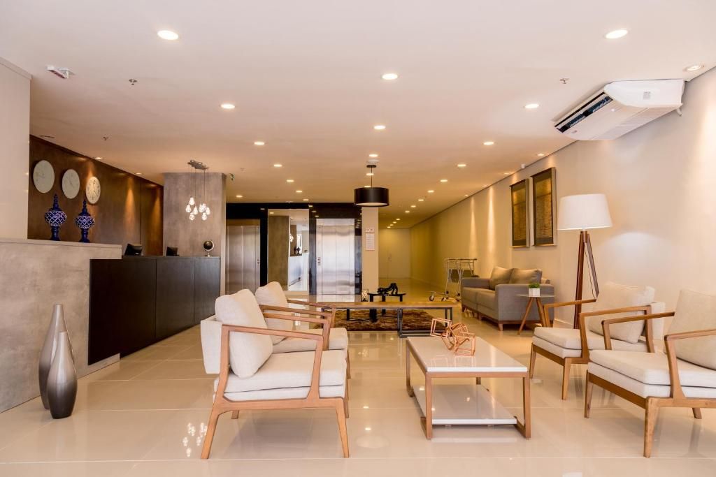 Saguão do hotel com área de estar, balcão de recepção e esquema de cores neutras.