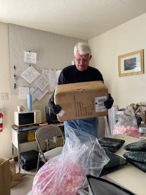 A man is holding a cardboard box in a room.