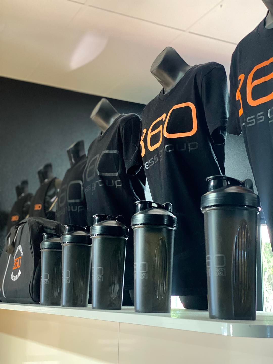 Display of Black Shirts and Shakers With Orange Logo in a Store; Fitness Apparel — 360 Fitness Group in Gordonvale, QLD