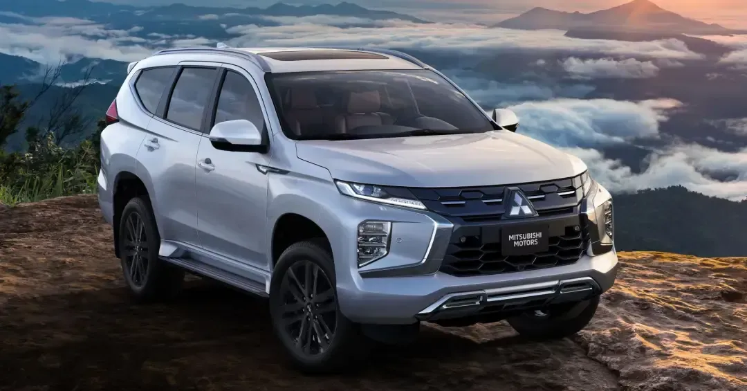Silver Mitsubishi SUV parked on a hillside with mountain background.