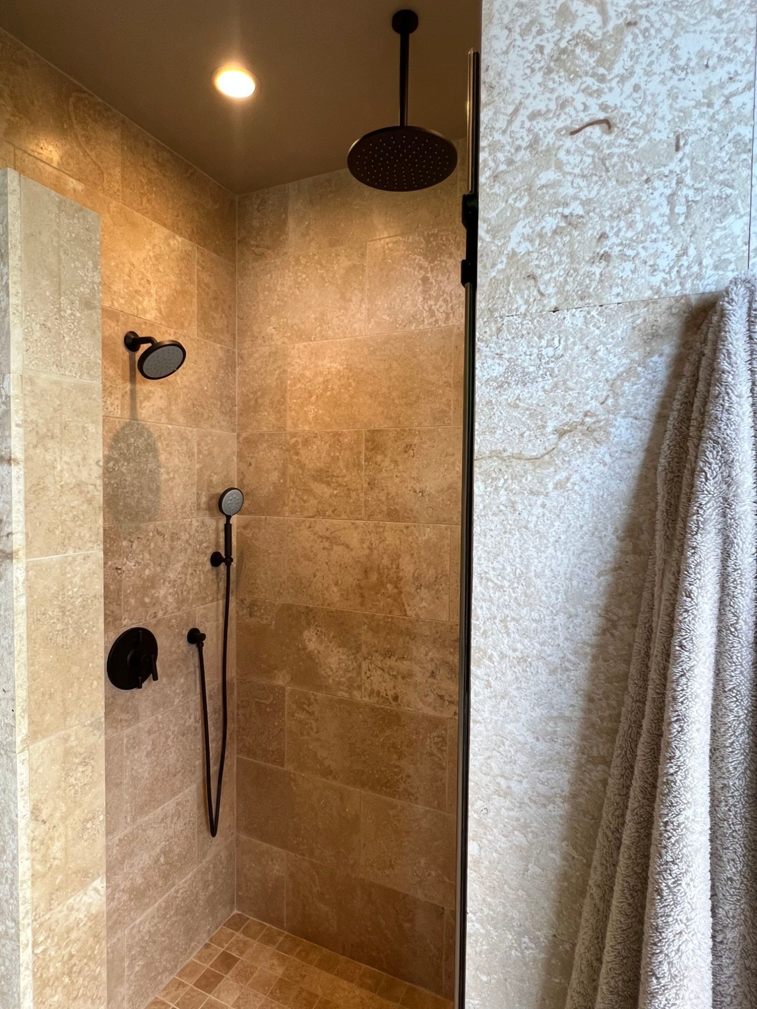 Plumber using a wrench to install a chrome faucet on a bathtub.