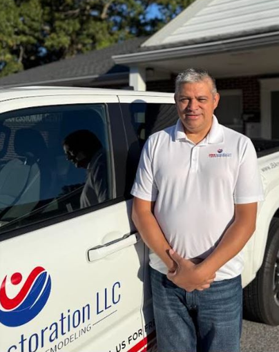 Man stands beside a white truck with the company logo 