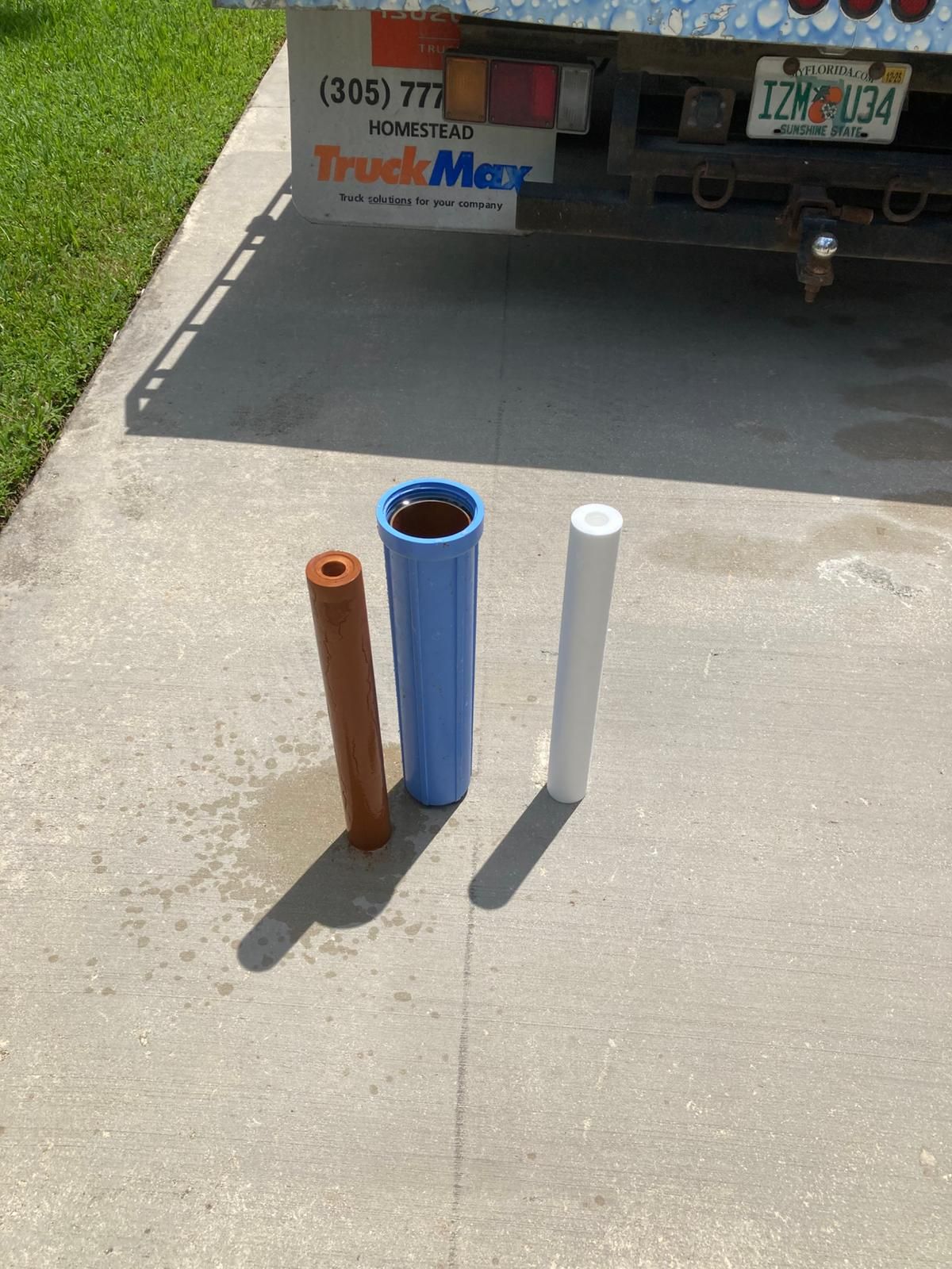 Three water filters on concrete with a truck in the background.