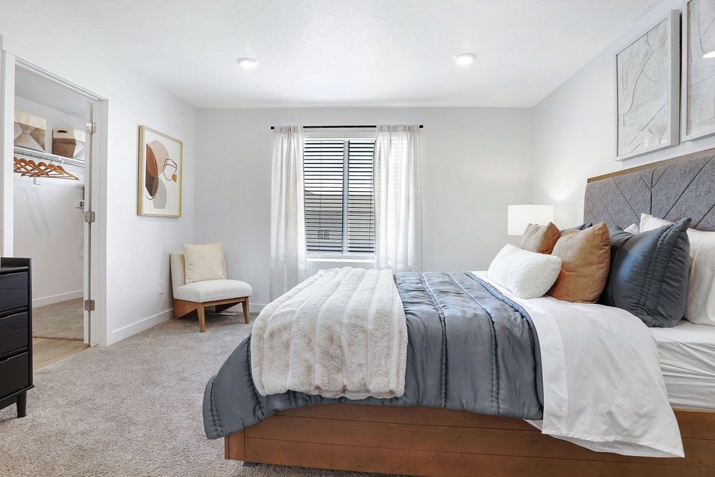 Bedroom in apartment with a large bed, gray bedding, and an open closet to the left.