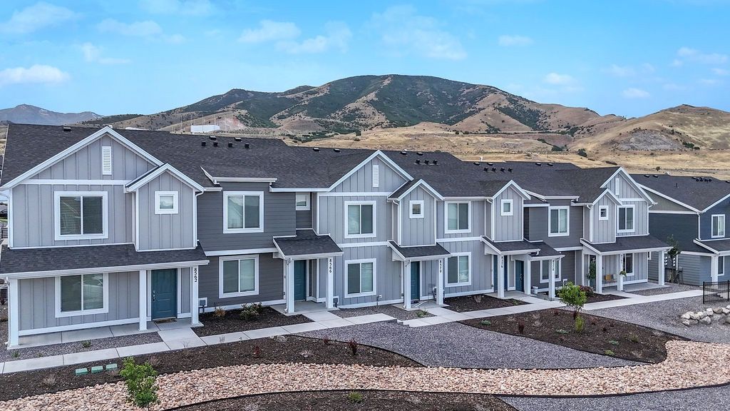 Row of gray townhouse-style apartment buildings with desert landscaping and hills in the background