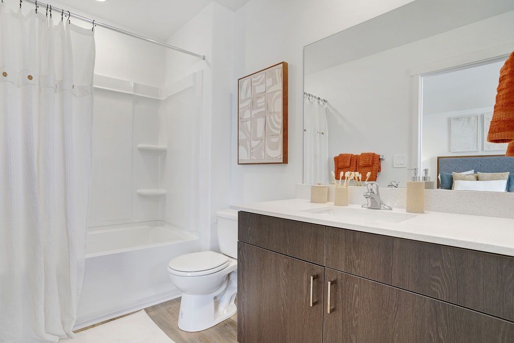 Bathroom with white tile, shower curtain, toilet, and dark wood vanity with a large mirror.