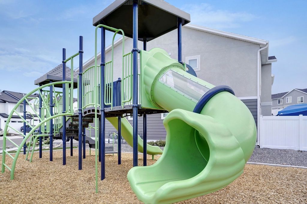 Playground structure with a bright green curved slide in a residential complex.