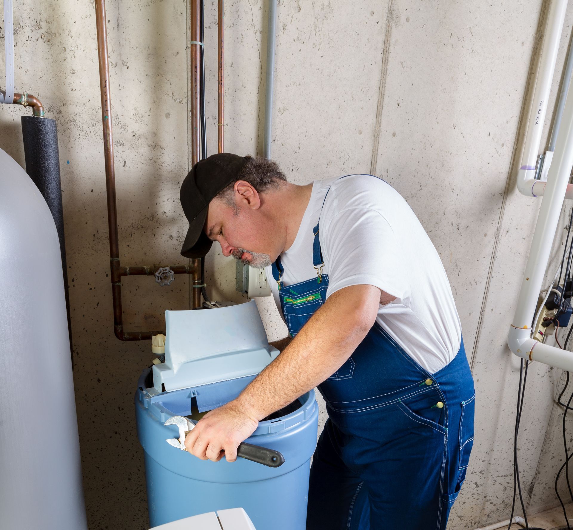 a plumber reaches inside the water softener to install it 