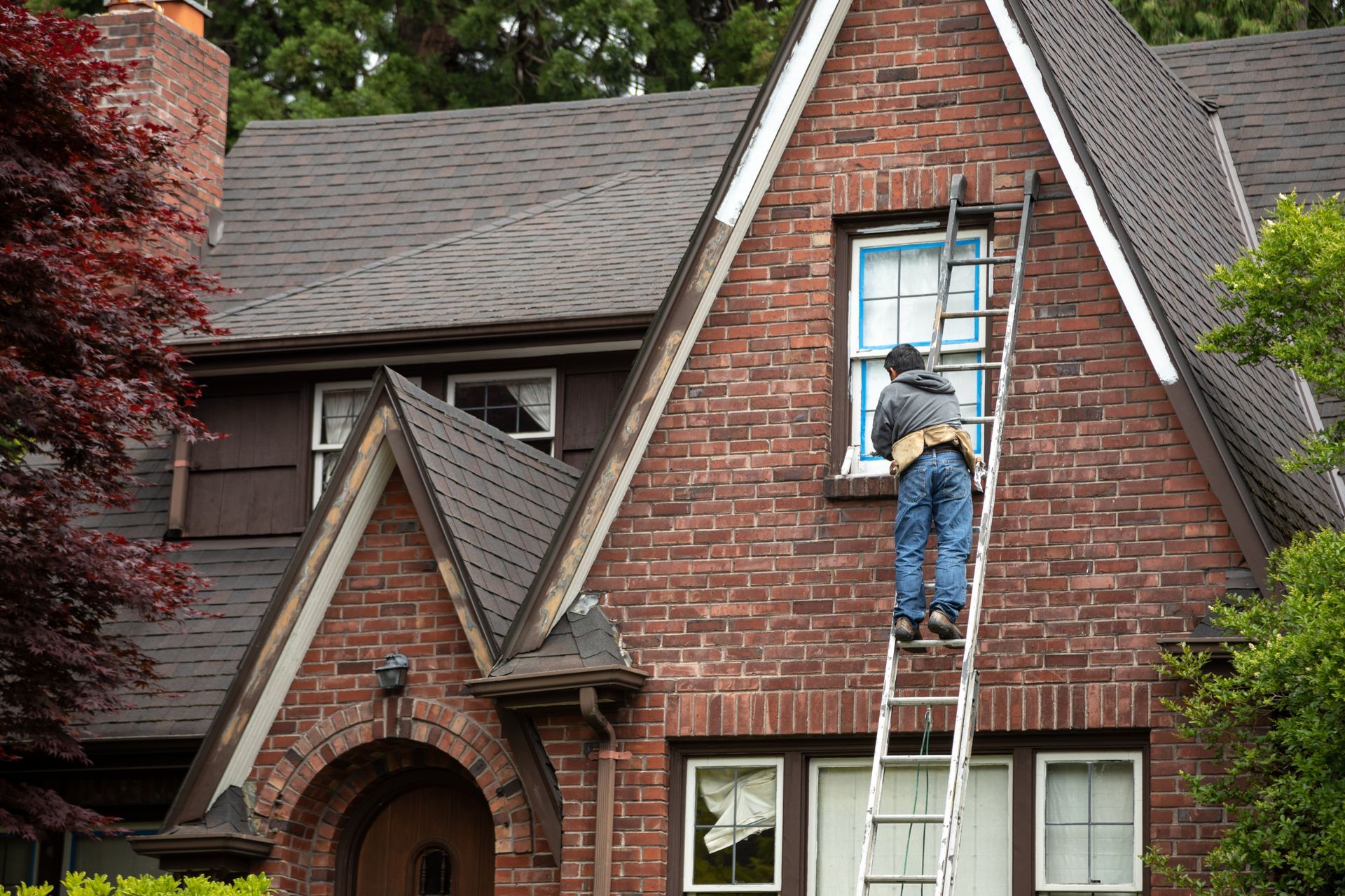 A man on a ladder is performing maintenance on historic windows