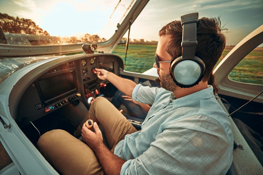 the pilot, on their path to becoming a commercial pilot, adjusts the flight instruments in the cockpit of the plane