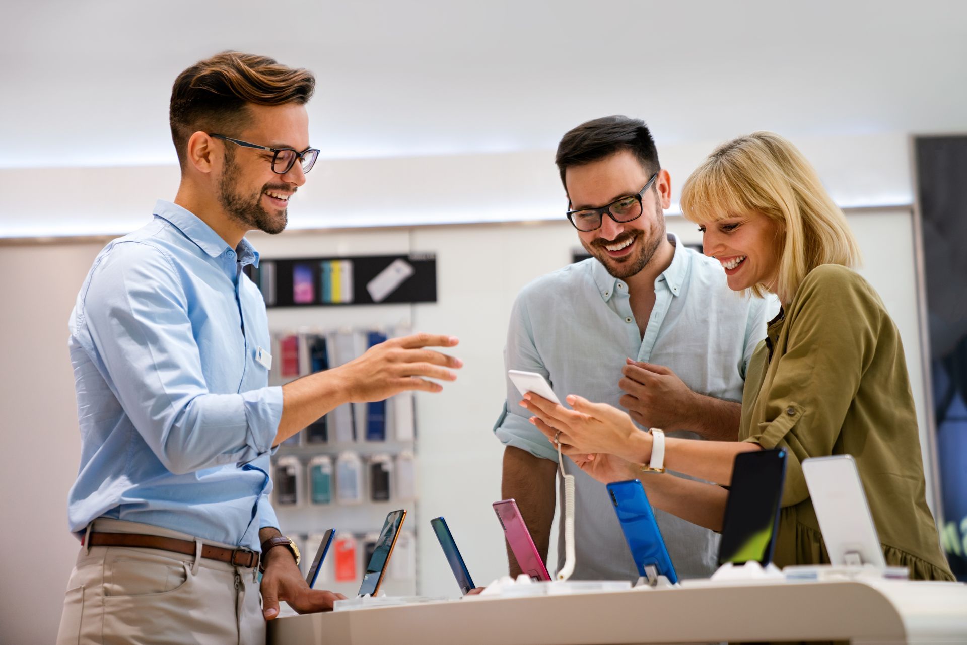 a man and a woman are looking at a cell phone in a store with the help of a sales associate showing the importance of great customer service