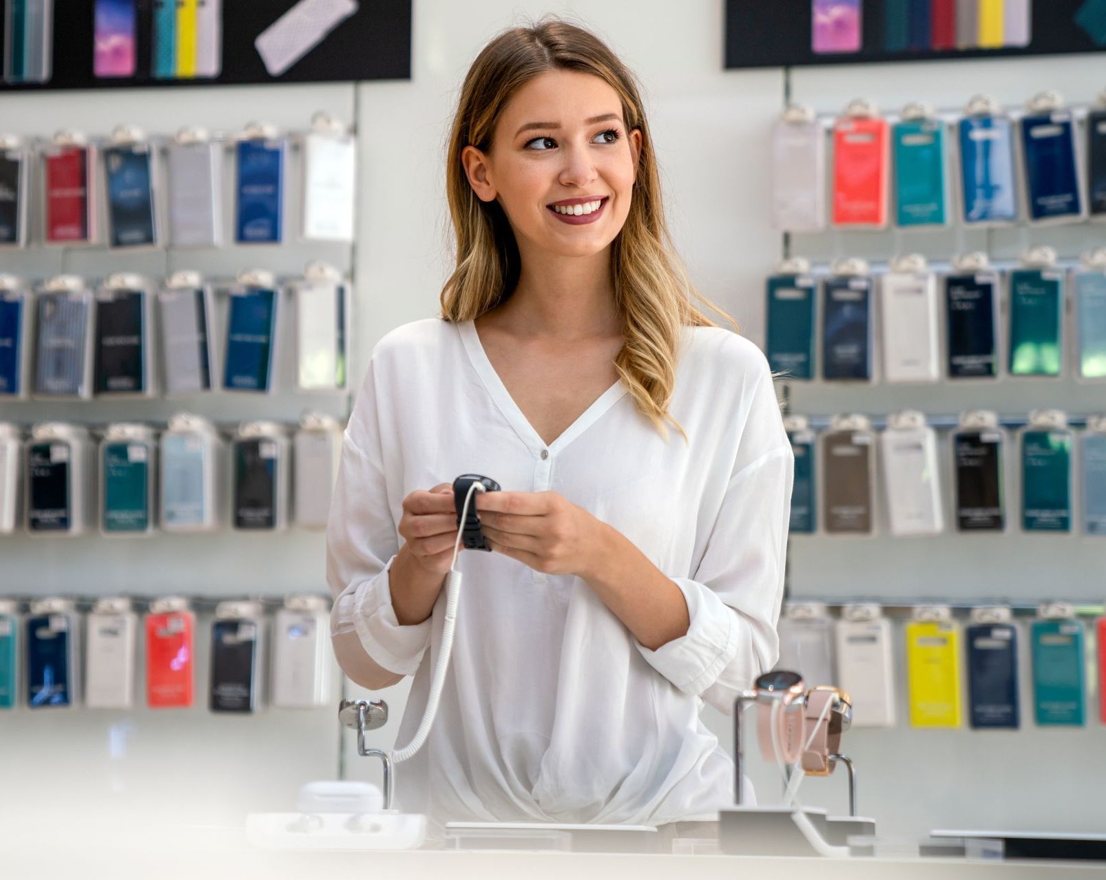 a woman in a white shirt is shopping for a smart device, she wants to become a customer advocate because of the great customer service she's recieved