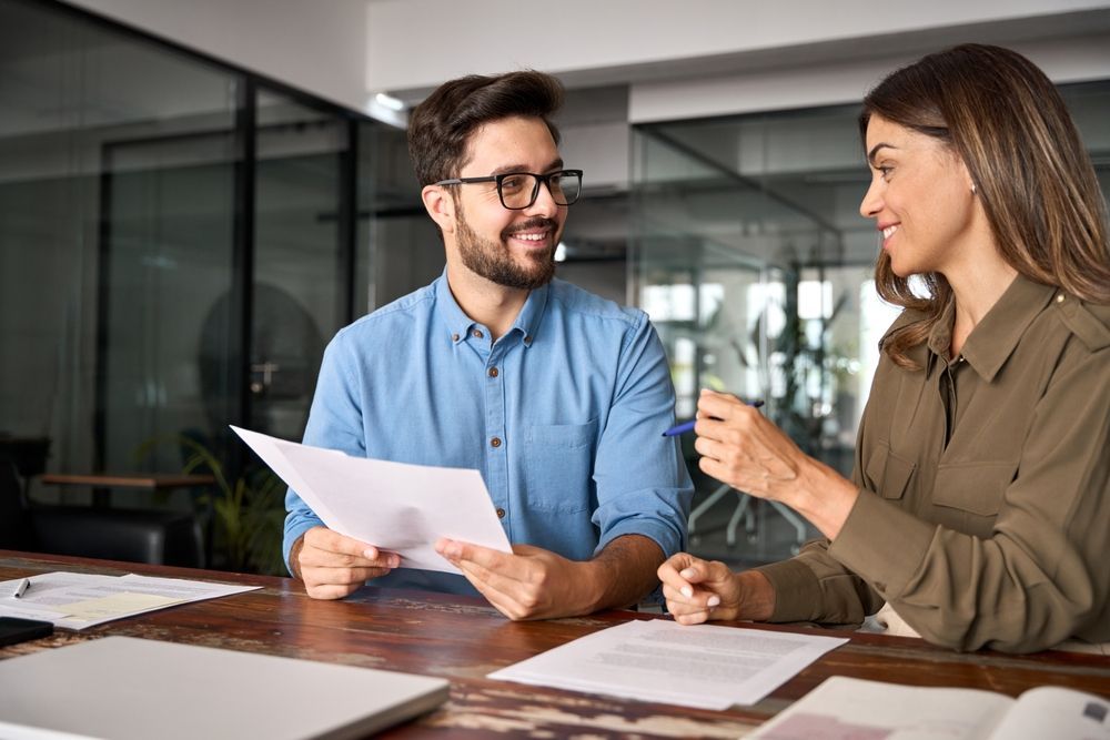 A man and a woman are sitting at a table looking at a piece of paper.