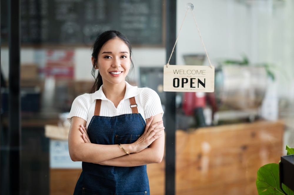 A woman is standing in front of an open sign in a restaurant.