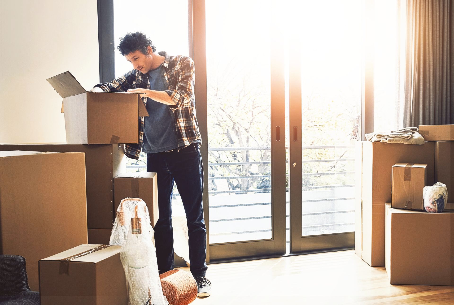 A man is standing in a room filled with cardboard boxes going through important documents