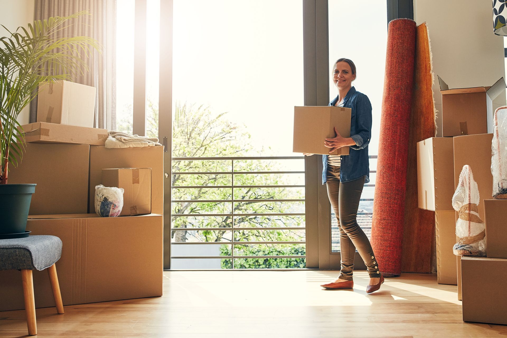 A woman is carrying a cardboard box into a new home.