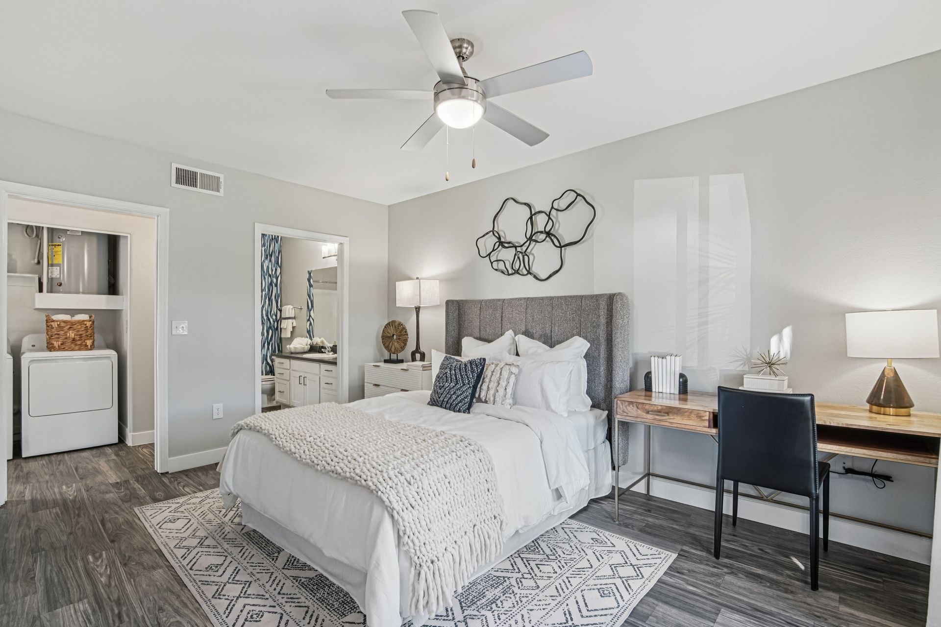 Bedroom with a bed, desk, and attached bathroom. Gray walls, rug, and flooring.