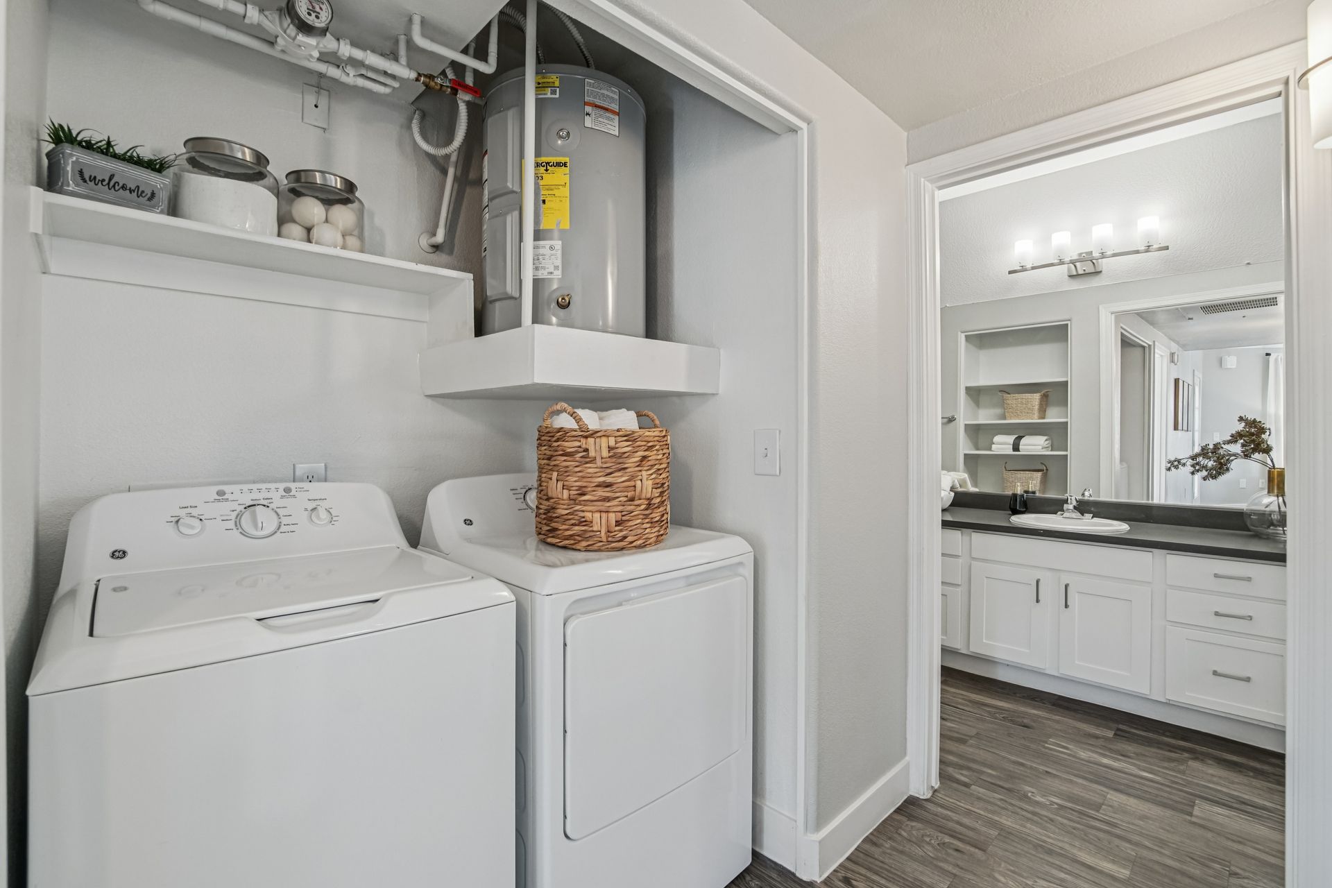 Laundry room with white washer and dryer, water heater, and a view into a bathroom.