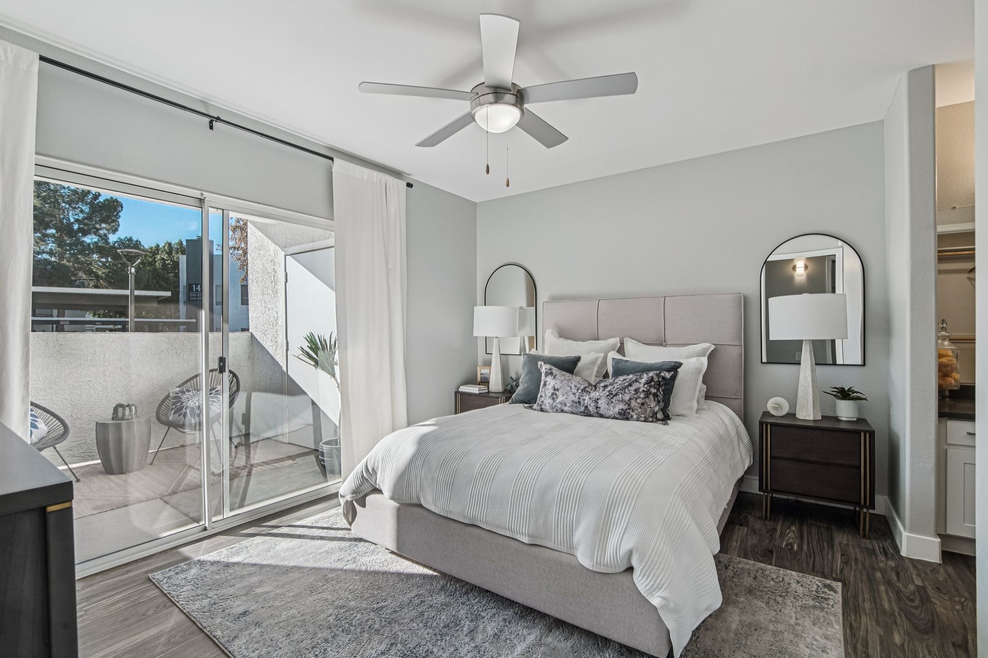 Bedroom with bed, balcony, and ceiling fan. Gray walls, white bedding, rug, and dark wood nightstands.