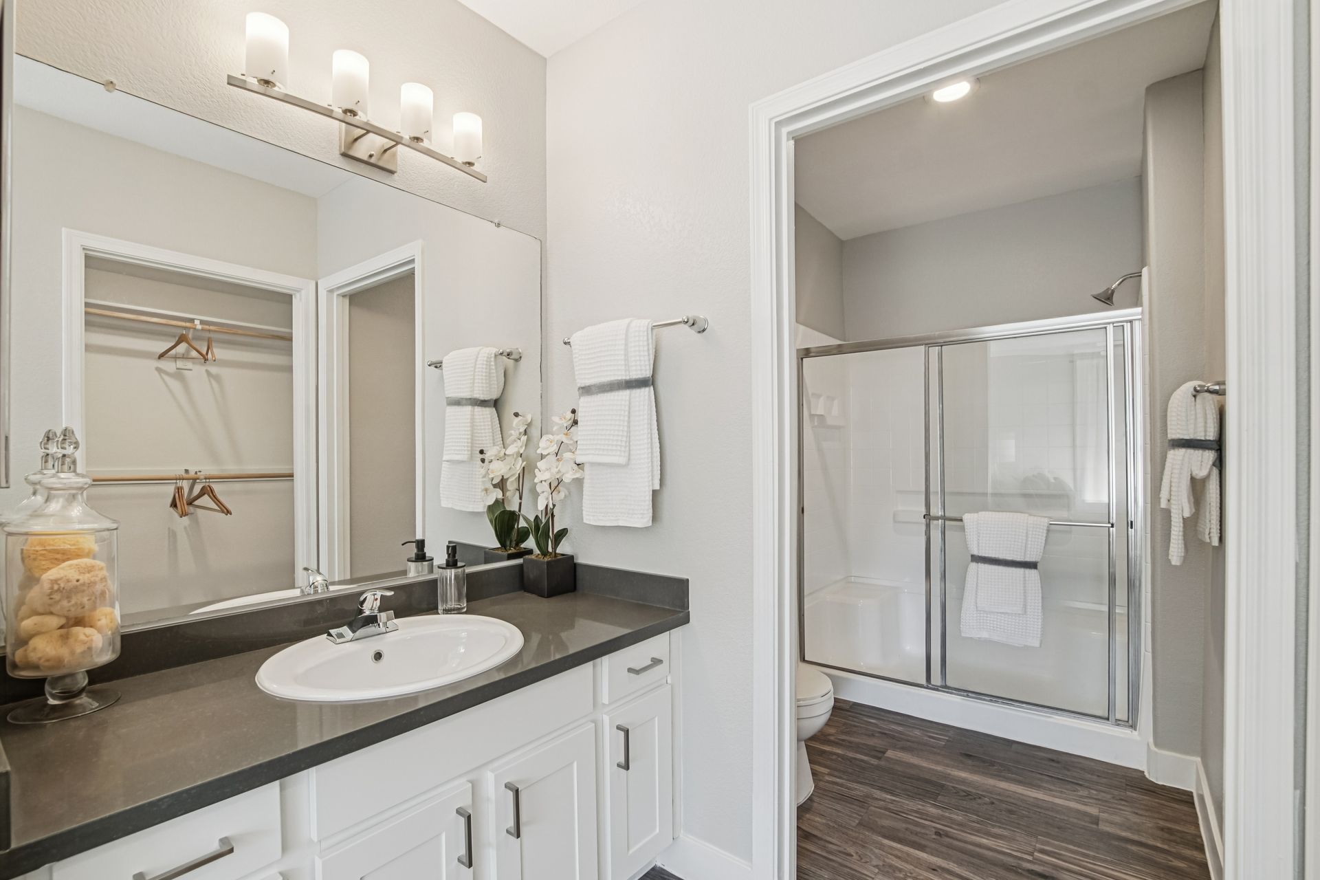Bathroom with white cabinets, dark countertop, and walk-in shower.