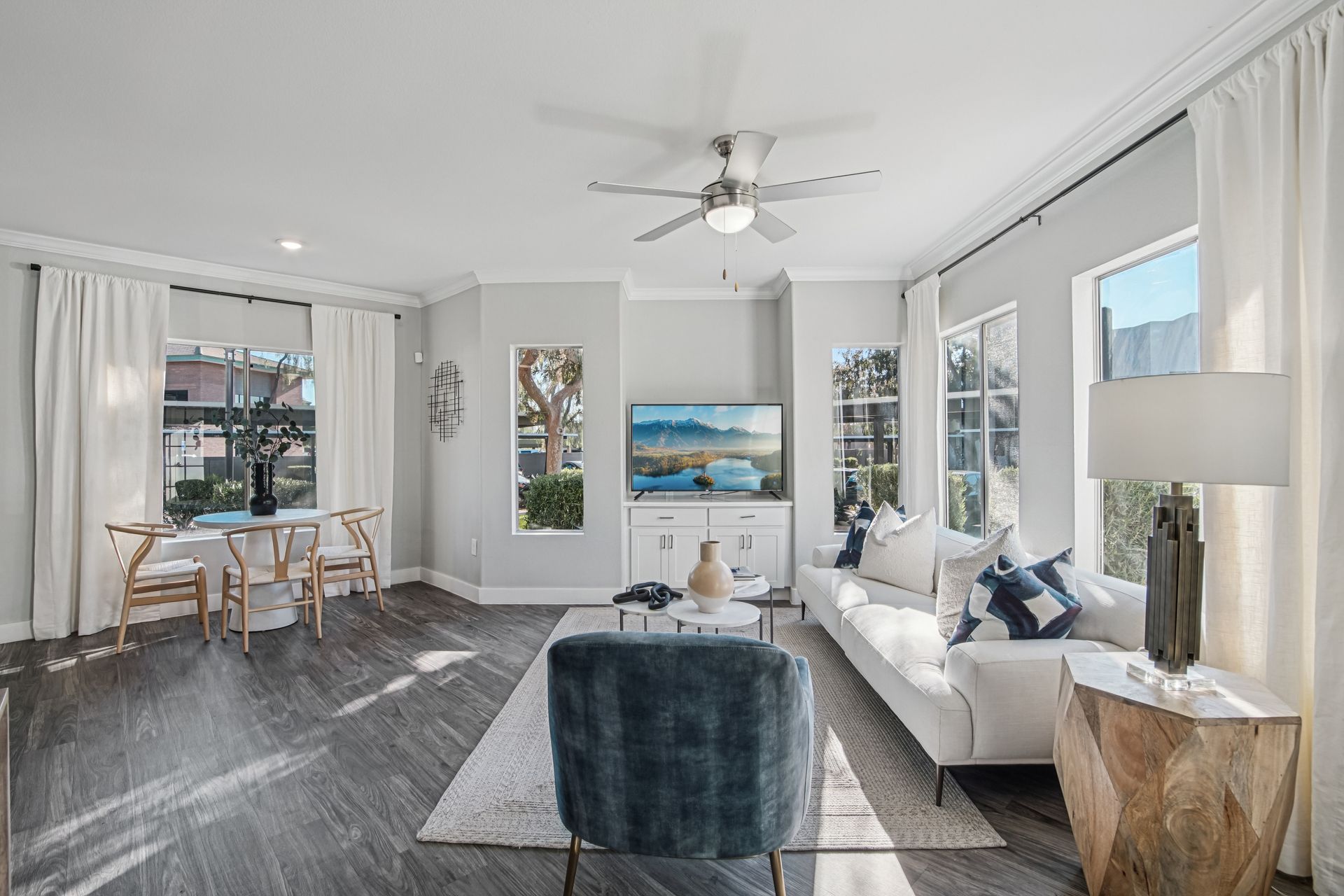Living room with hardwood floors, white sofa, window, and TV.