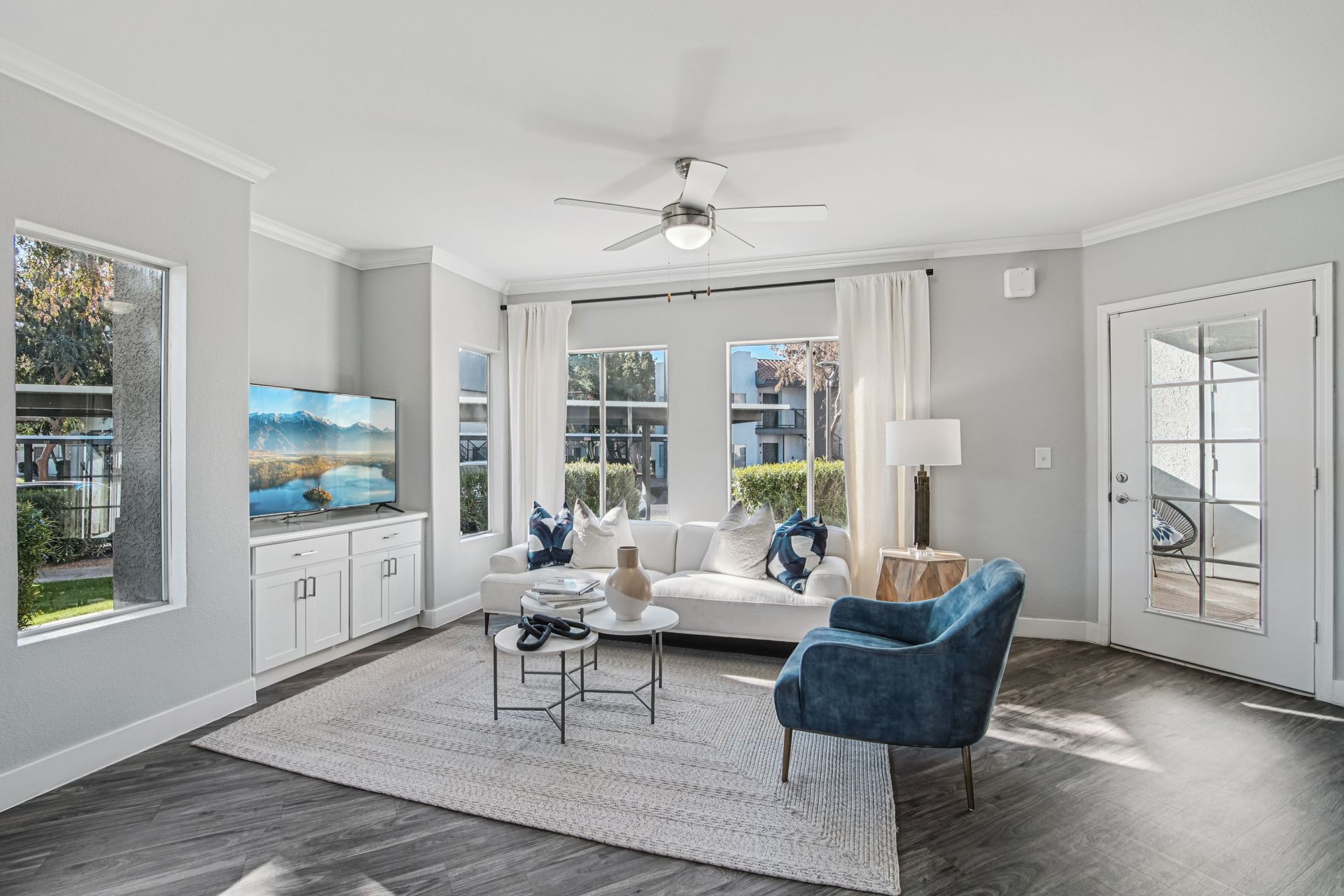 Living room with white walls, gray floors, and a blue armchair.