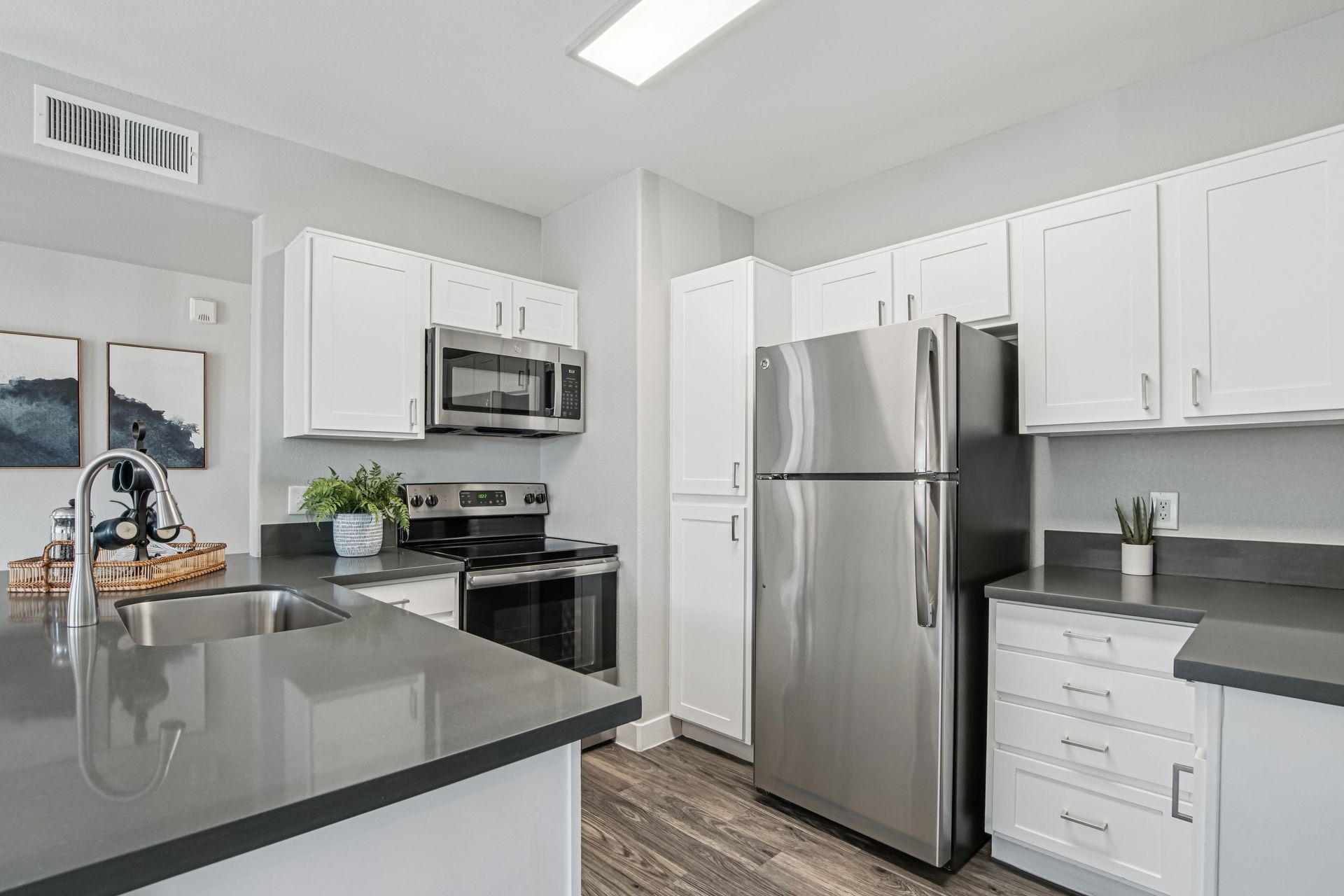 Modern kitchen with stainless steel appliances, white cabinets, and gray countertops.