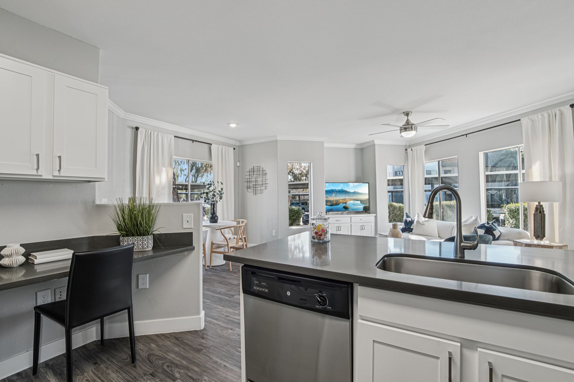 Modern apartment interior with a kitchen island, desk, and living area.