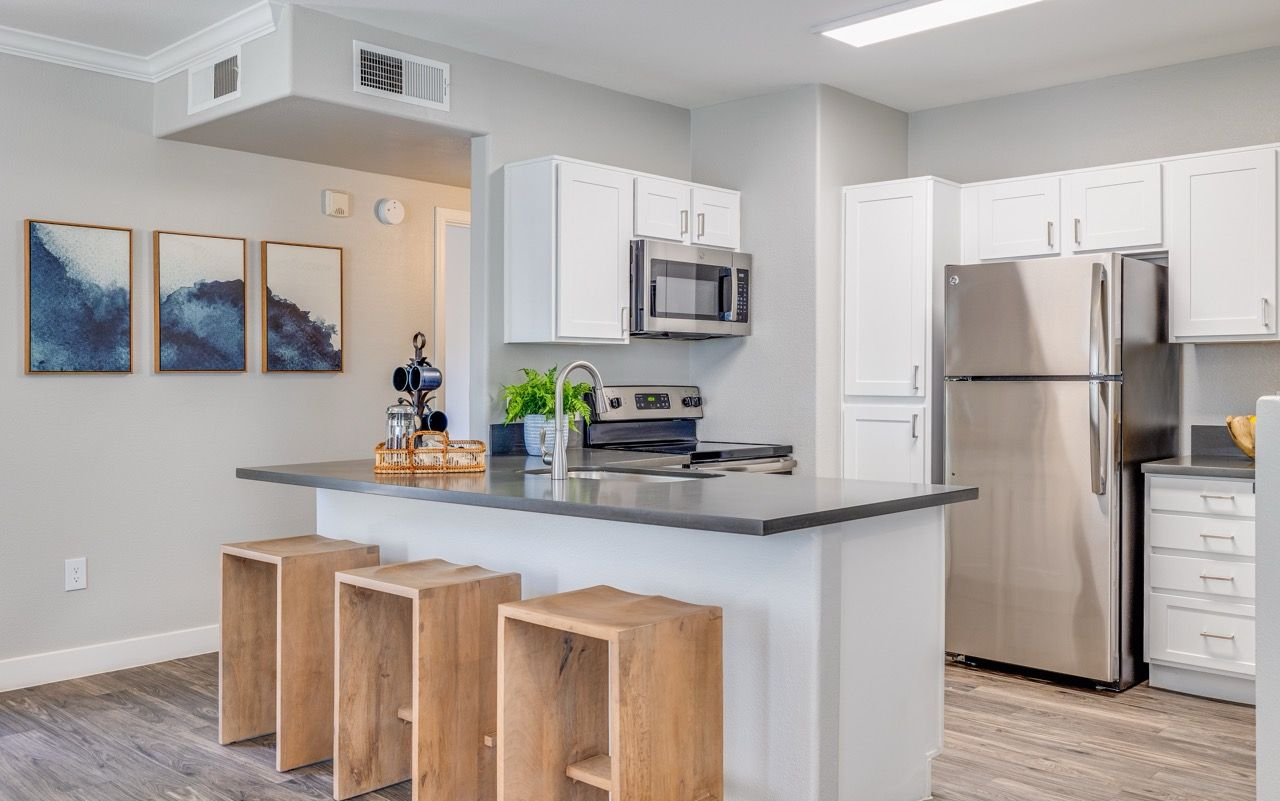 Open-concept kitchen in a modern apartment with an island, white cabinets, and stainless steel appliances.
