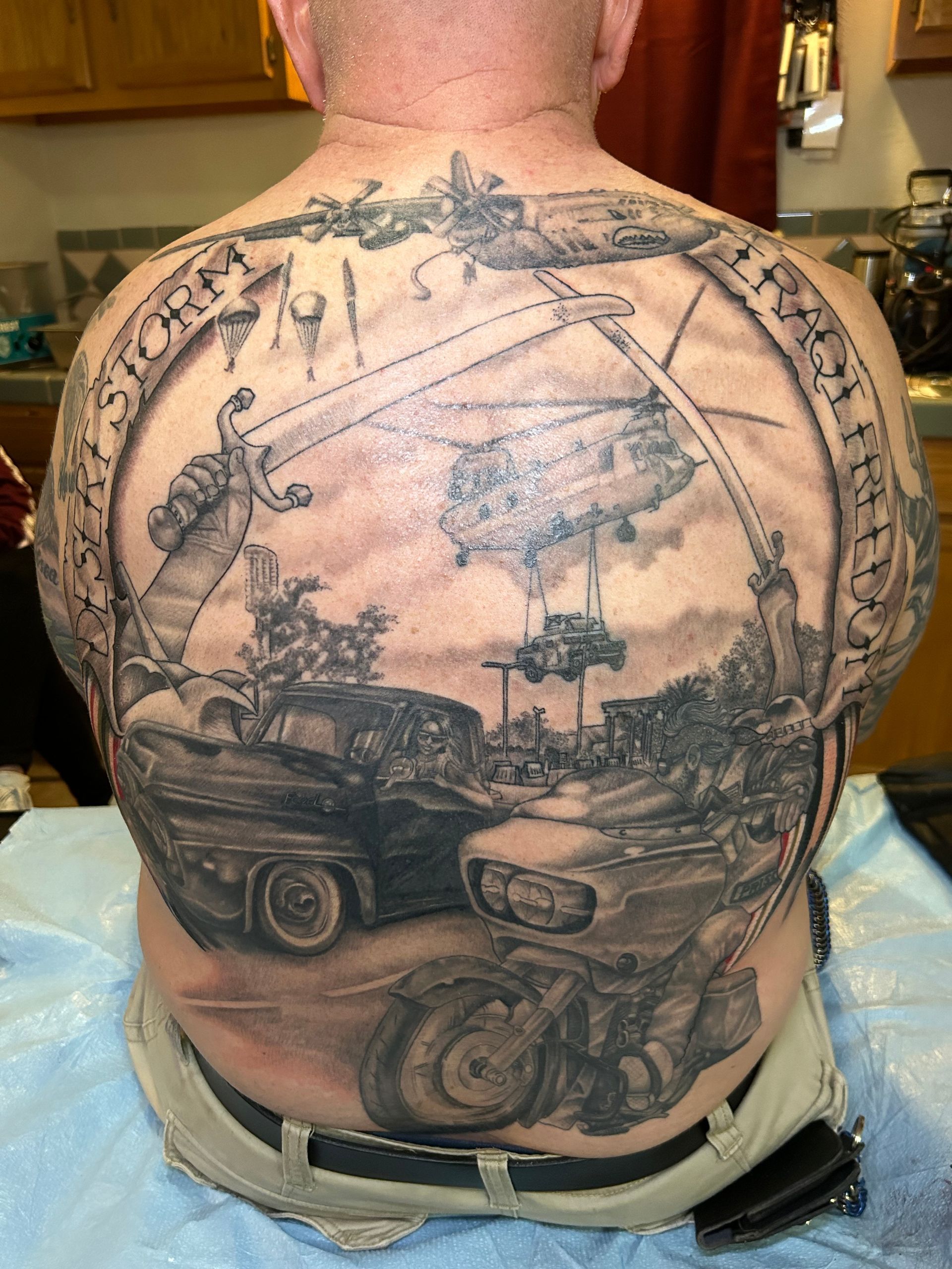 Back tattoo with cars, a motorcycle, and zeppelins inside a circle, with text.