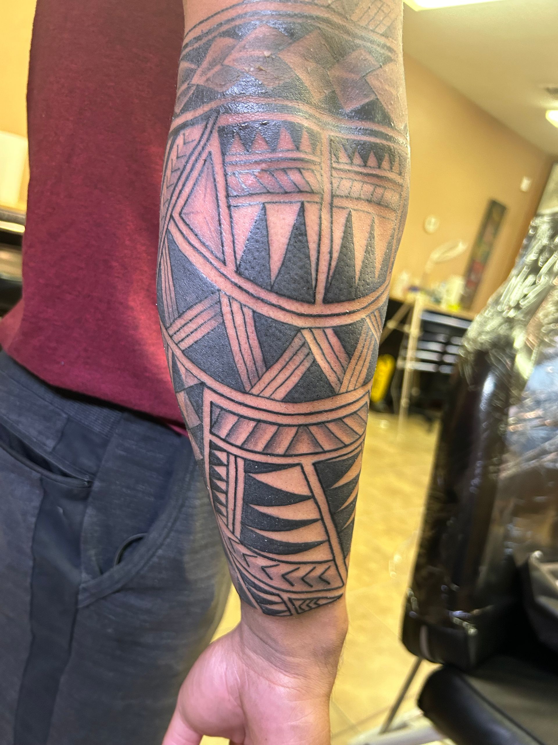 Tattoo of black geometric tribal patterns covering a person's forearm, showcasing intricate designs.