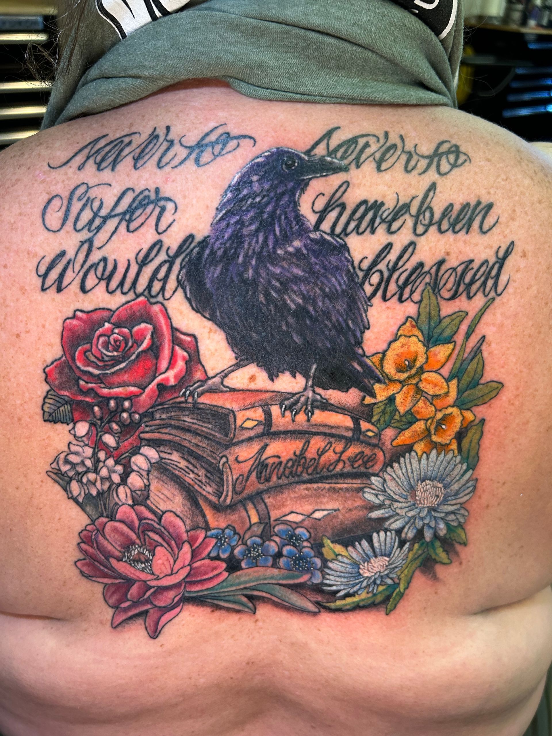 Tattoo: Raven atop books, surrounded by flowers, with cursive text.