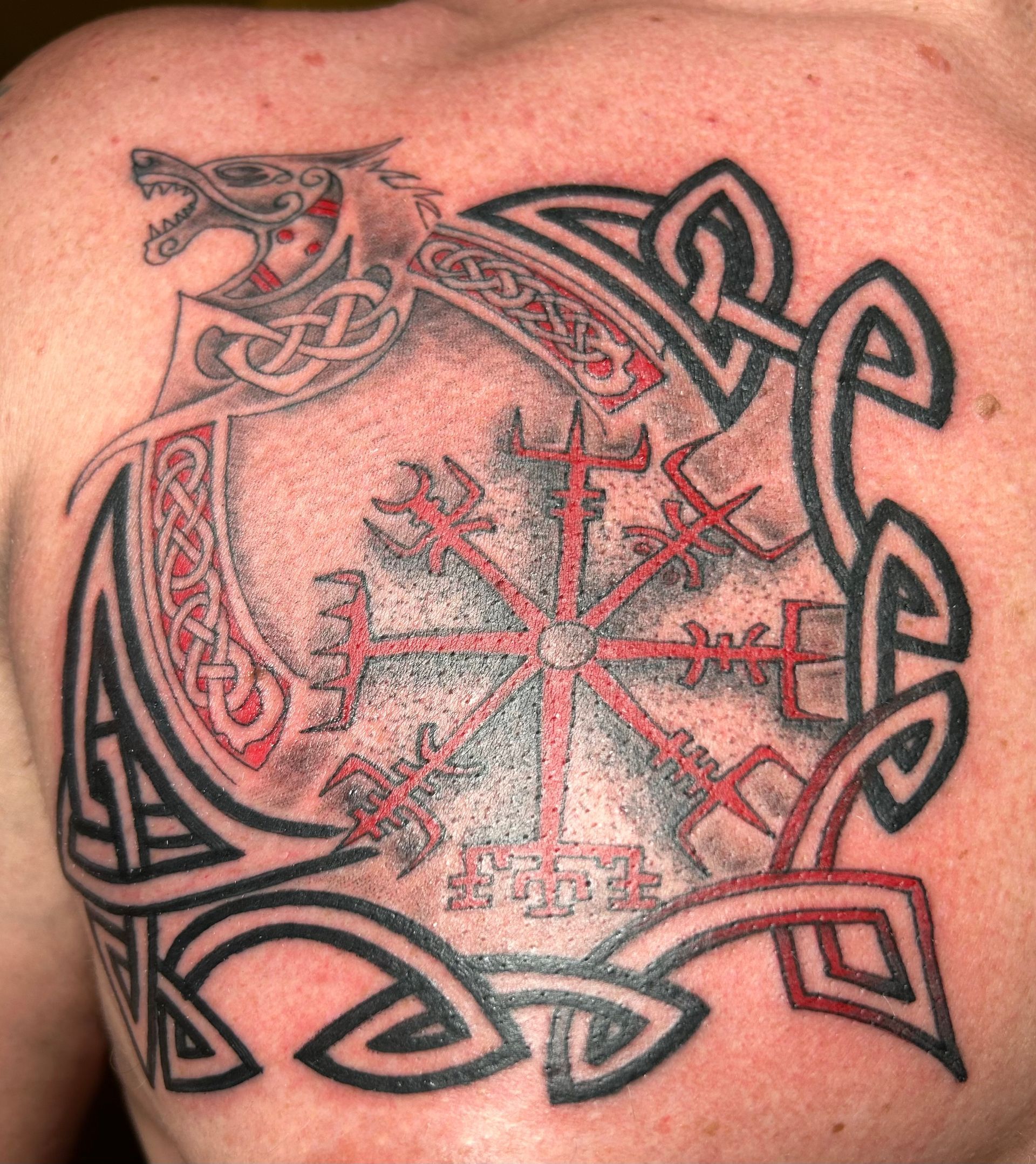 Chest tattoo: Viking symbol, wolf, knotwork, and red/black design.