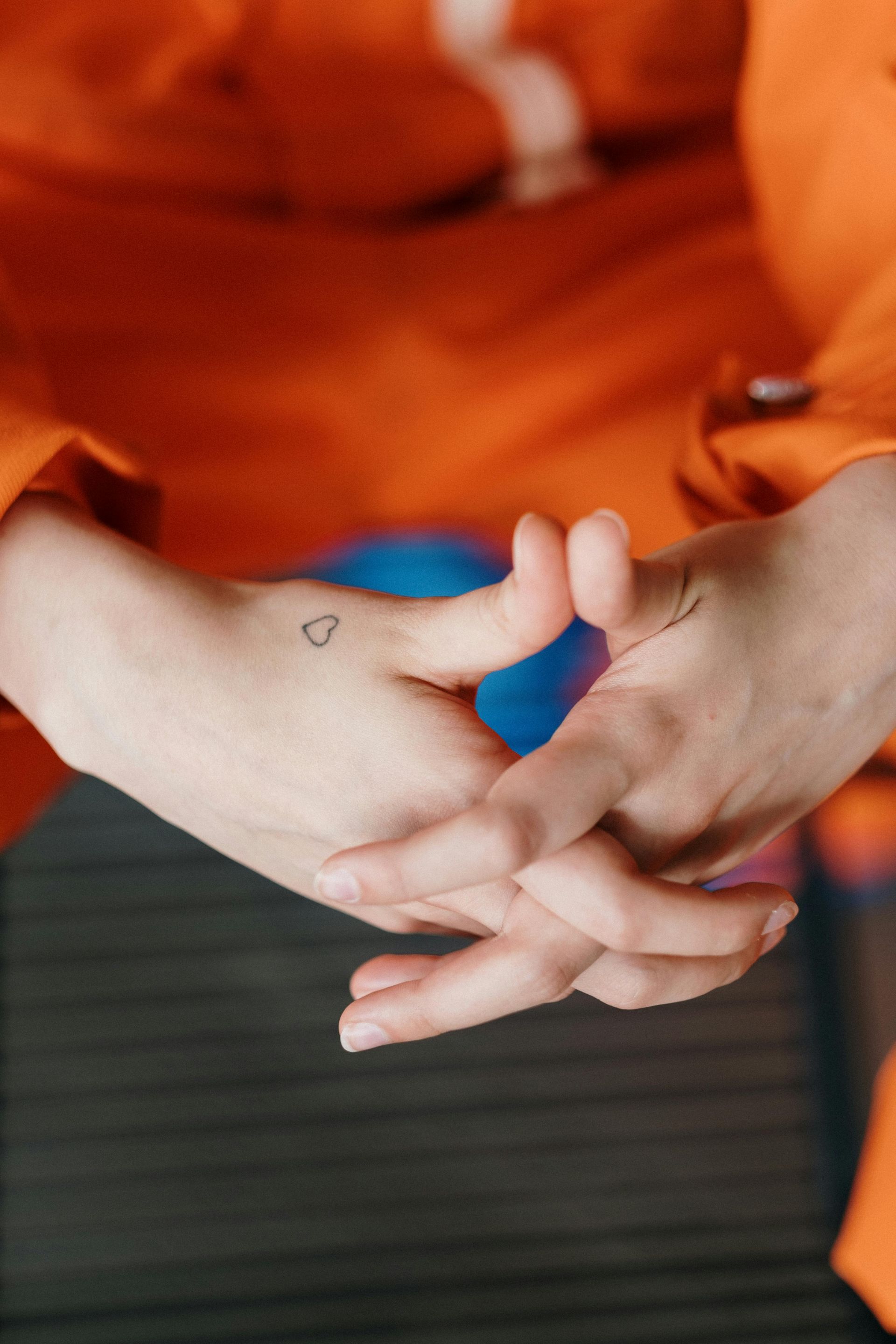 Neck of person with a small, black outline tattoo of a spray paint can nozzle.