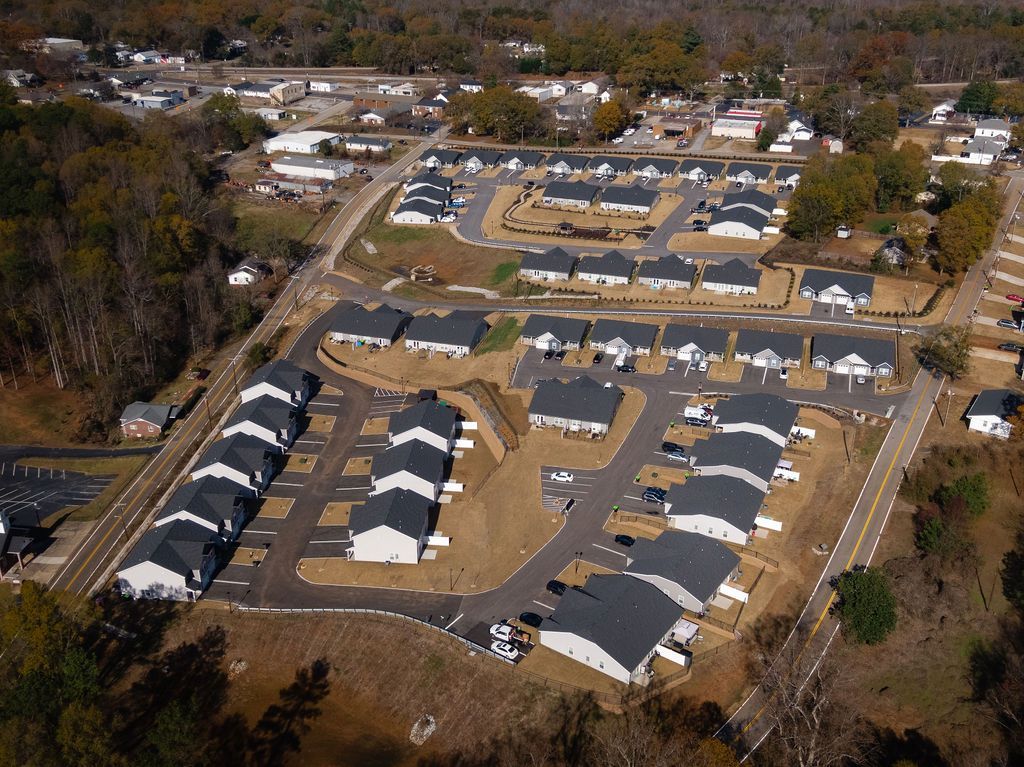 Gazebo in a park setting with houses in the background. Features a playground and landscaping.