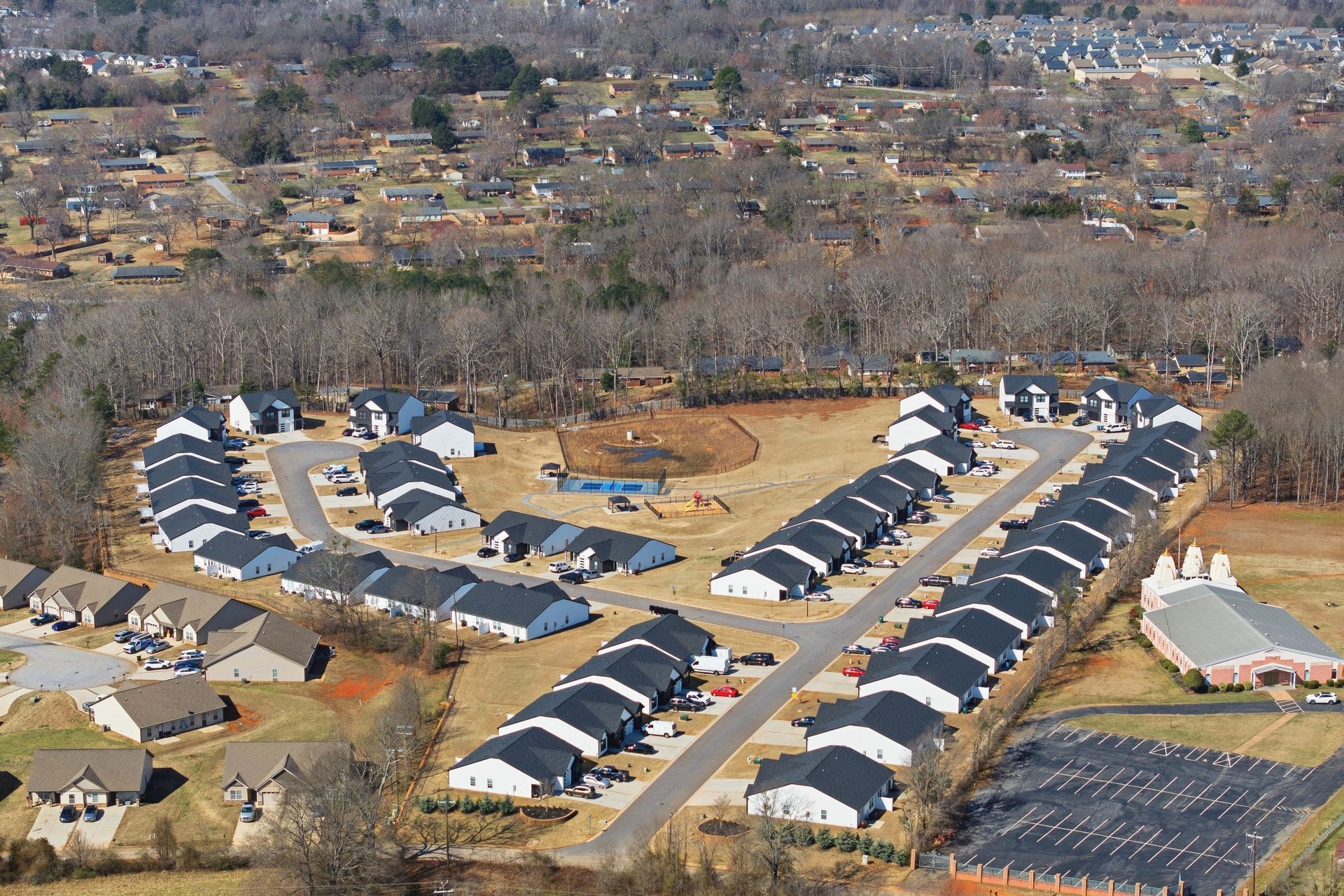 Modern duplex with dark gray and white siding, concrete driveway, and a cloudy sky.