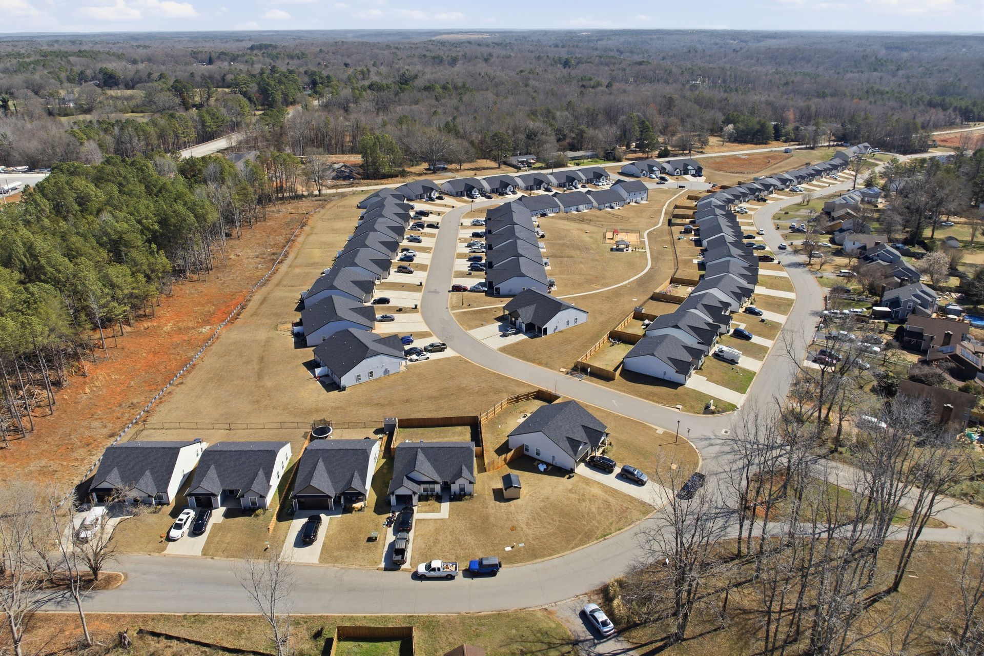 Modern duplex with gray and white siding, garages, and a concrete driveway under a blue sky.