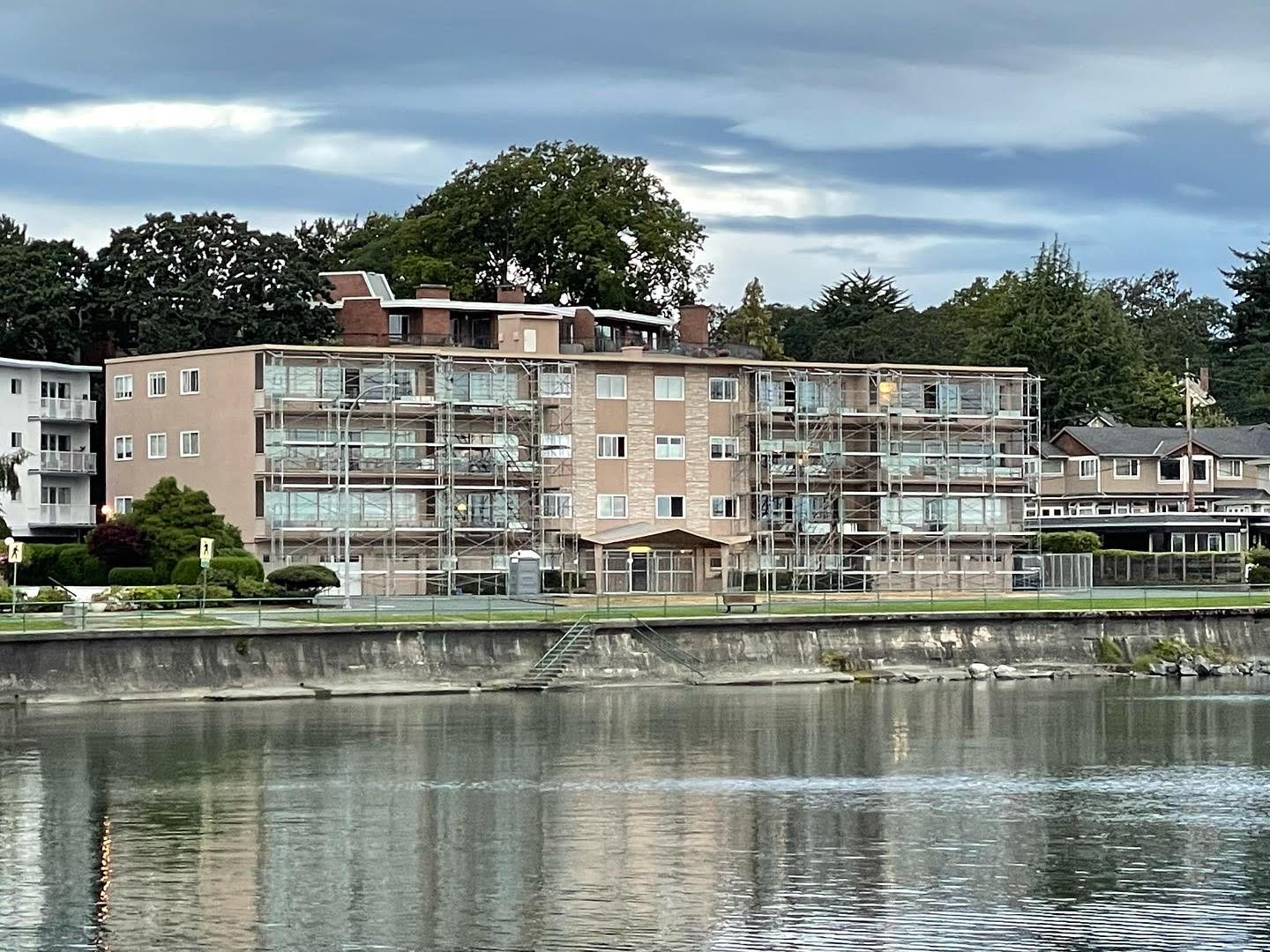 A large apartment building is next to a body of water.