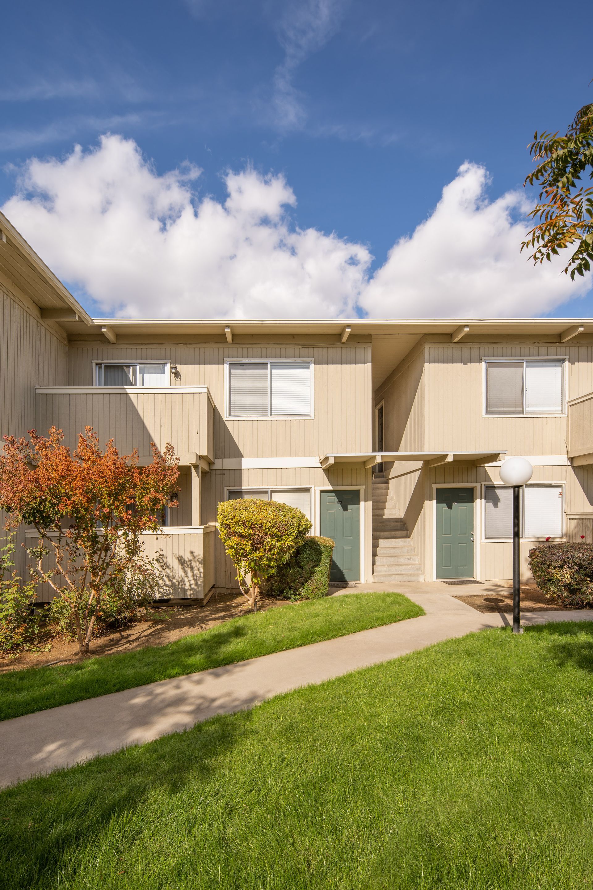 Townhomes with a grassy path and blue sky.