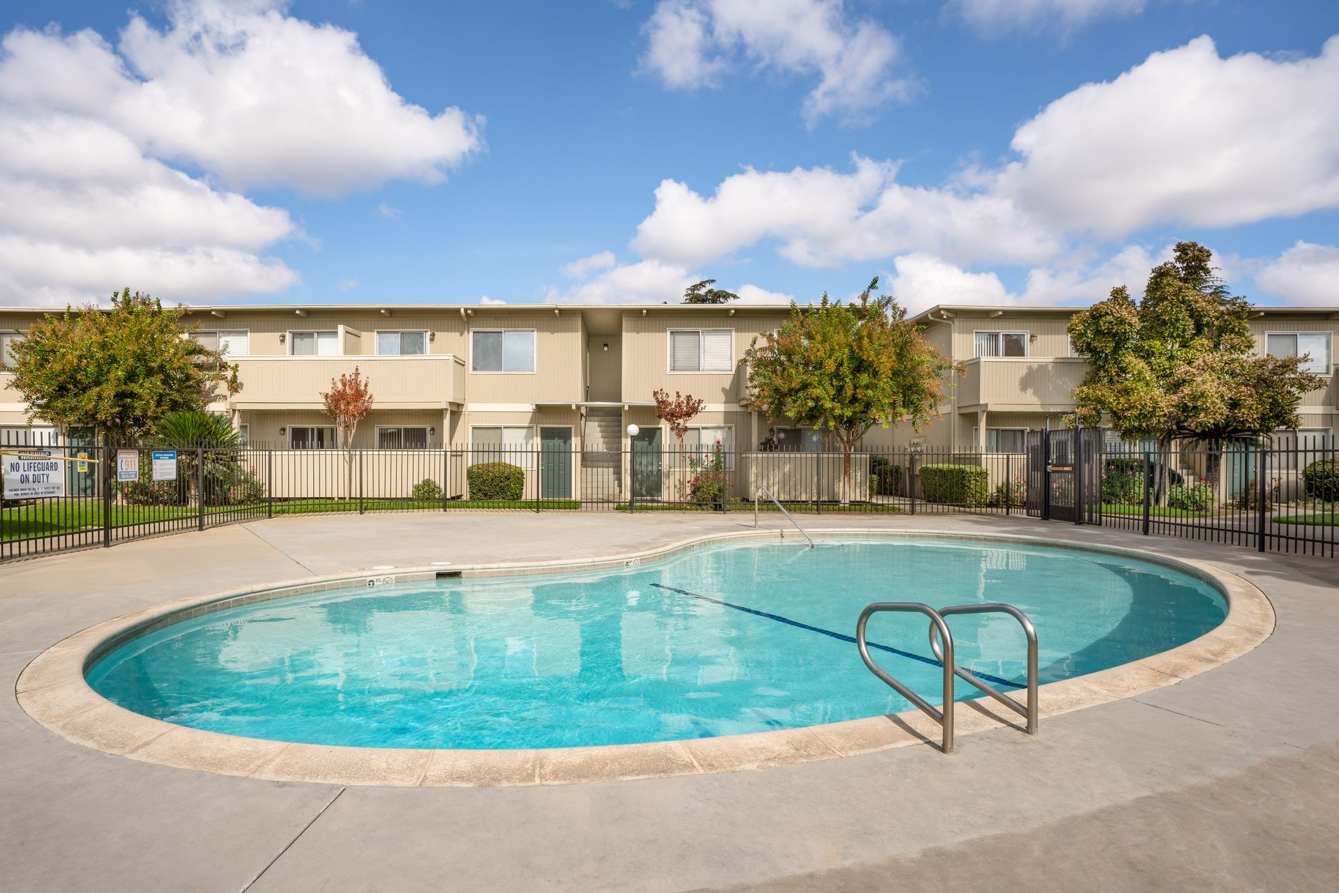 Apartment complex with a kidney-shaped pool on a sunny day.