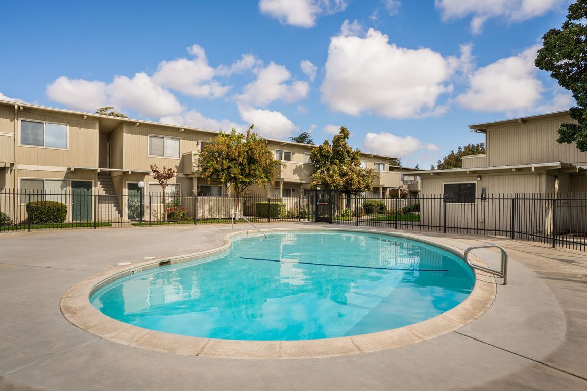 Apartment complex with a turquoise pool on a sunny day.