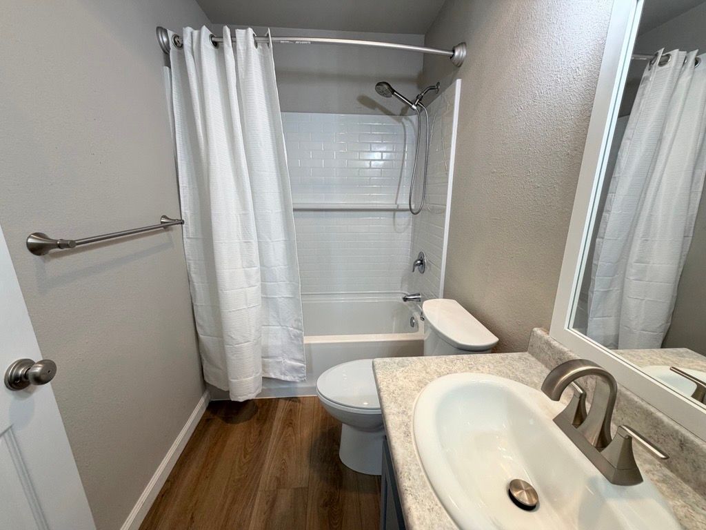 Bathroom with white shower curtain, sink, toilet, and towel rack.