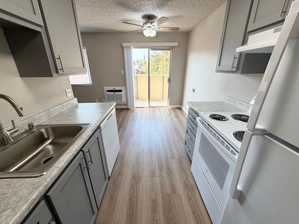 Kitchen with gray cabinets, white appliances, and a sliding glass door to a balcony.