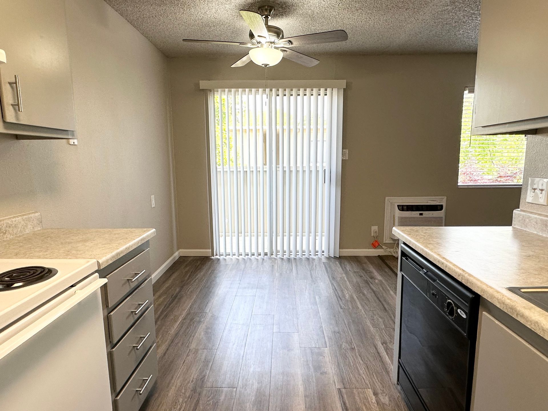 Kitchen interior with cabinets, stove, dishwasher, and sliding glass door to a patio.